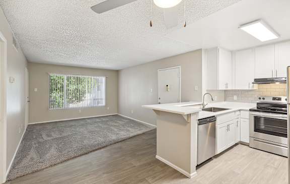 an empty kitchen and living room with white cabinets and a window